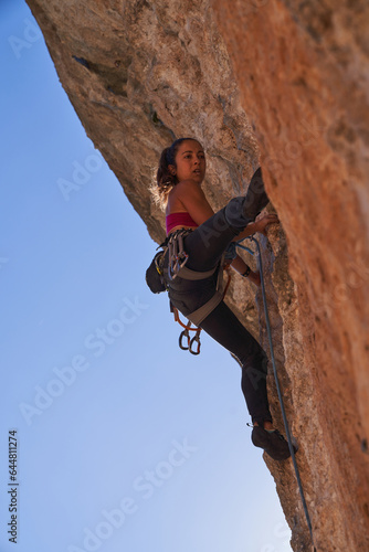 Sportswoman climbing mountain using special equipment