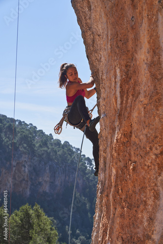 Woman climbing sheer cliff using special equipment