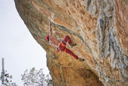 Faceless strong climber holding onto rock while hanging on rope