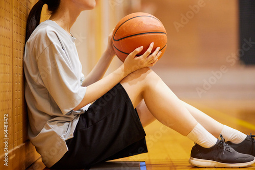 体育館でバスケットボールの練習をするスポーツウェアを着た日本人女性