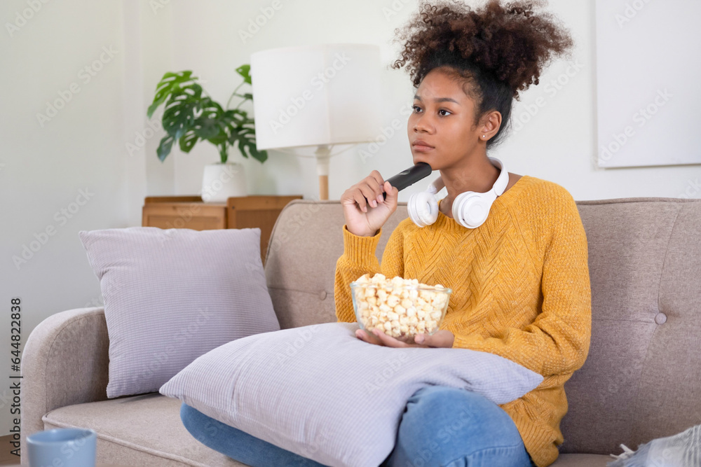 Young woman relishes film watching on living room couch.