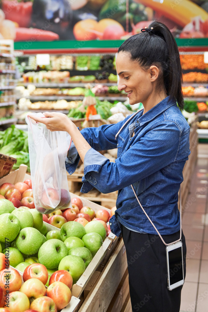 Delightful Hispanic woman buying apples in grocery store