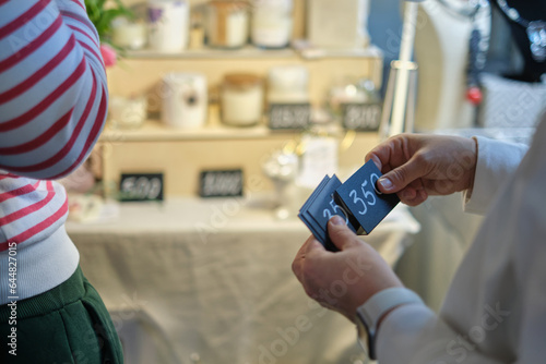 Small Business, Big Dreams: Under a sunlit canopy, a woman entrepreneur meticulously adjusts price labels on her booth's display, each tag reflecting the value of her hard work and creative vision