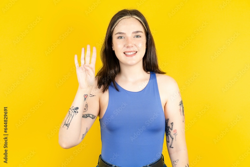 Beautiful woman wearing blue tank top showing and pointing up with fingers number four while smiling confident and happy.