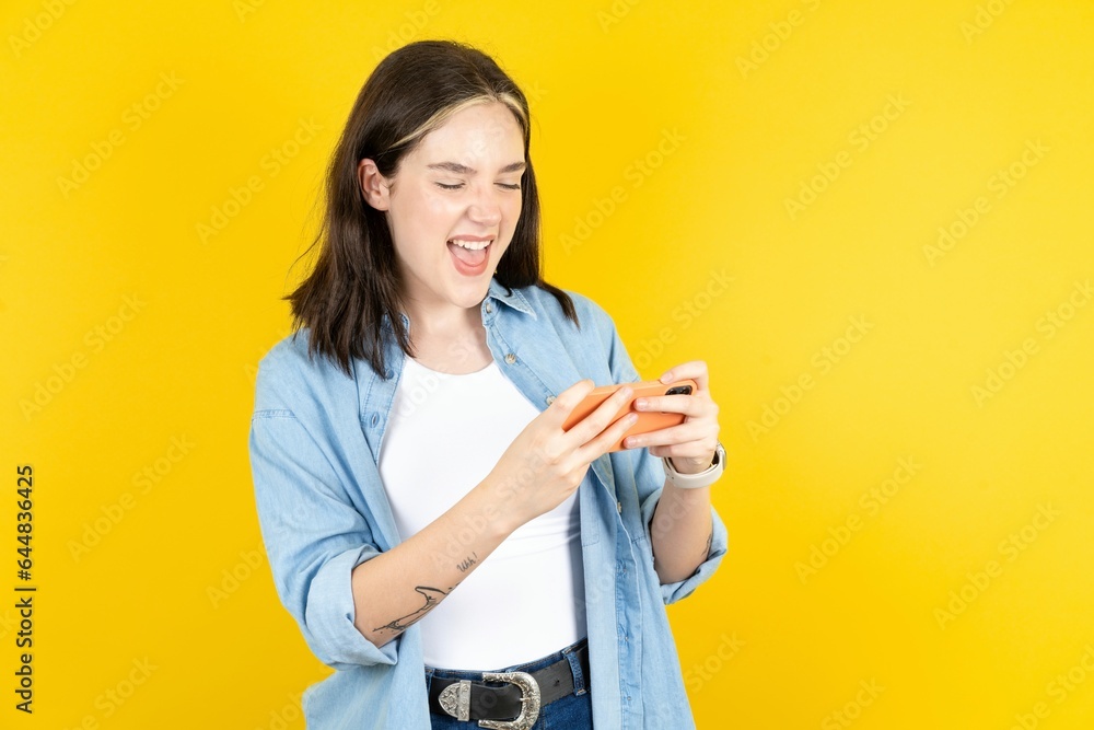 Beautiful woman wearing casual clothes holding in hands cell playing video games or chatting Beautiful woman wearing casual clothes holding in hands cell playing video games or chatting