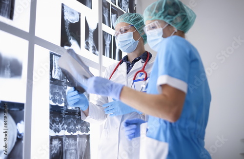 Obraz na plátně Doctors in medical office wearing protective medical masks and gloves and glasses are examining X-rays