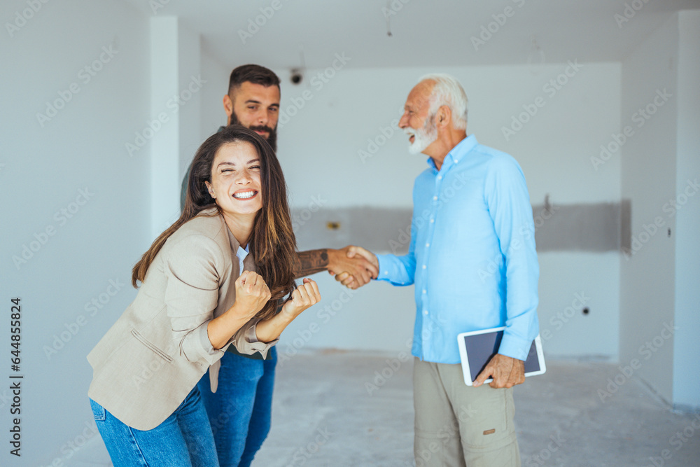Obraz premium Real Estate Agent showing a house under construction to a couple and greeting them with a handshake at a construction site. Estate Agent Greeting Couple During Visit To New Home