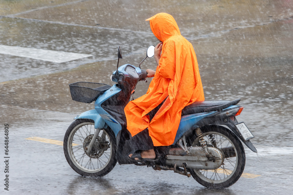 A man dressed in a raincoat rides a motorcycle in the heavy rain A man dressed in a raincoat rides a motorcycle in the heavy rain