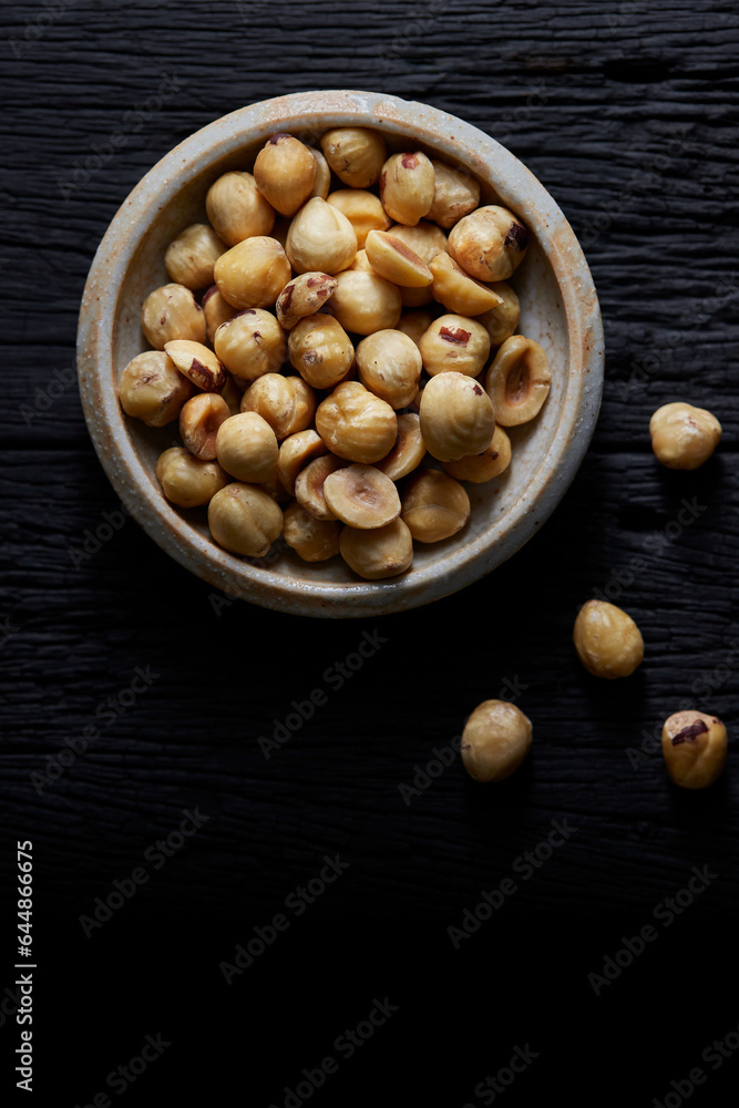 Hazelnut in small cup on black wooden background. Hazelnut in small cup on black wooden background.