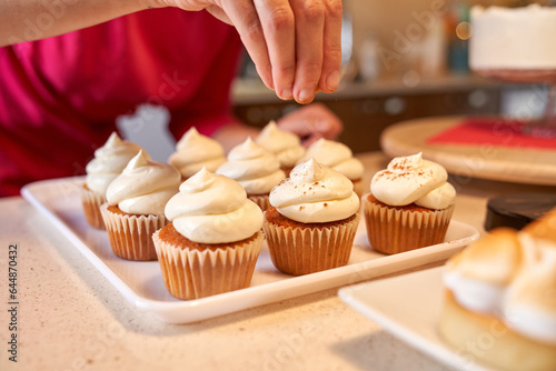 Crop confectioner making cupcakes in kitchen