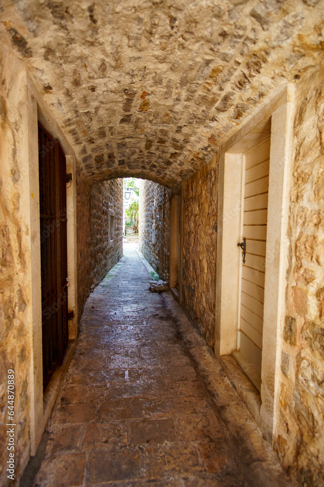 a narrow tunnel with an arch between houses on a narrow street, street view of the old town of Budva in Montenegro, medieval European architecture, the concept of traveling through the Balkans