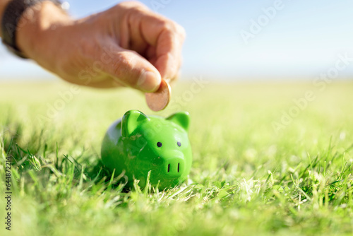 Saving money in green piggy bank, savings, accounting, banking and business account or sustainable and environmentally friendly finance photo