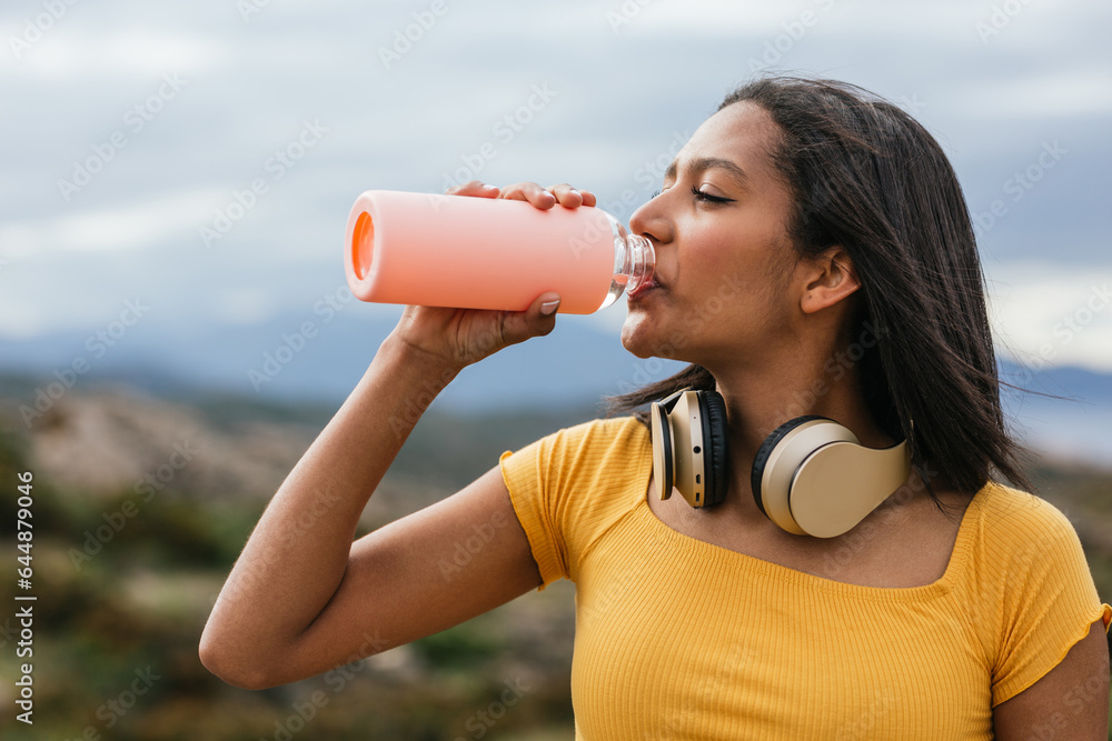 Ethnic woman drinking water from reusable bottle Ethnic woman drinking water from reusable bottle