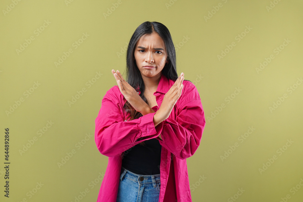 Portrait of asian woman serious strict cross hands sign x reject refuse choice decisions isolated over green color background Portrait of asian woman serious strict cross hands sign x reject refuse choice decisions isolated over green color background