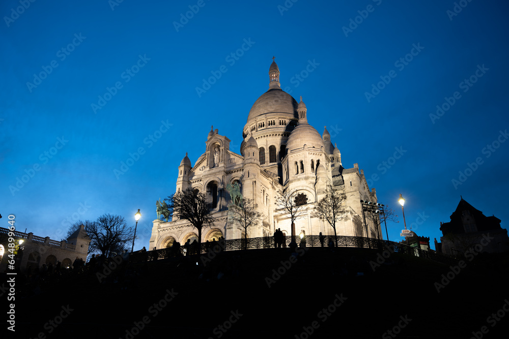The Basilica of Sacre Coeur de Montmartre illuminated in the evening. Roman Catholic church and minor basilica in Paris dedicated to the Sacred Heart of Jesus. France