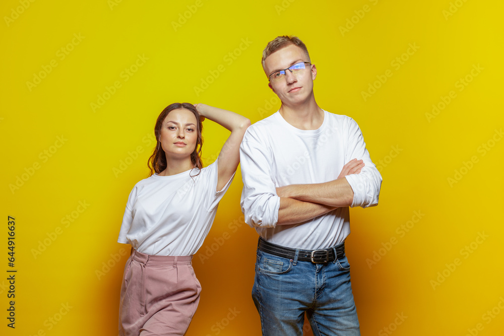 Strong couple woman and man standing against bright orange studio wall background Strong couple woman and man standing against bright orange studio wall background