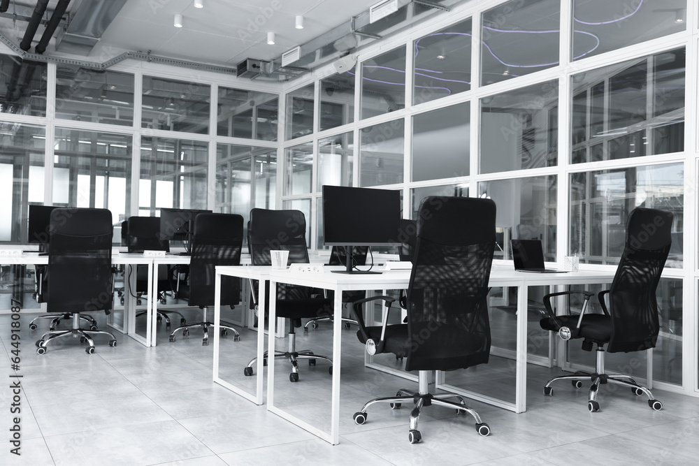 Stylish interior of open plan office. Workspace with computers, tables and chairs Stylish interior of open plan office. Workspace with computers, tables and chairs