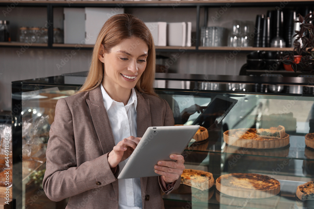 Happy business owner with tablet in bakery shop Happy business owner with tablet in bakery shop