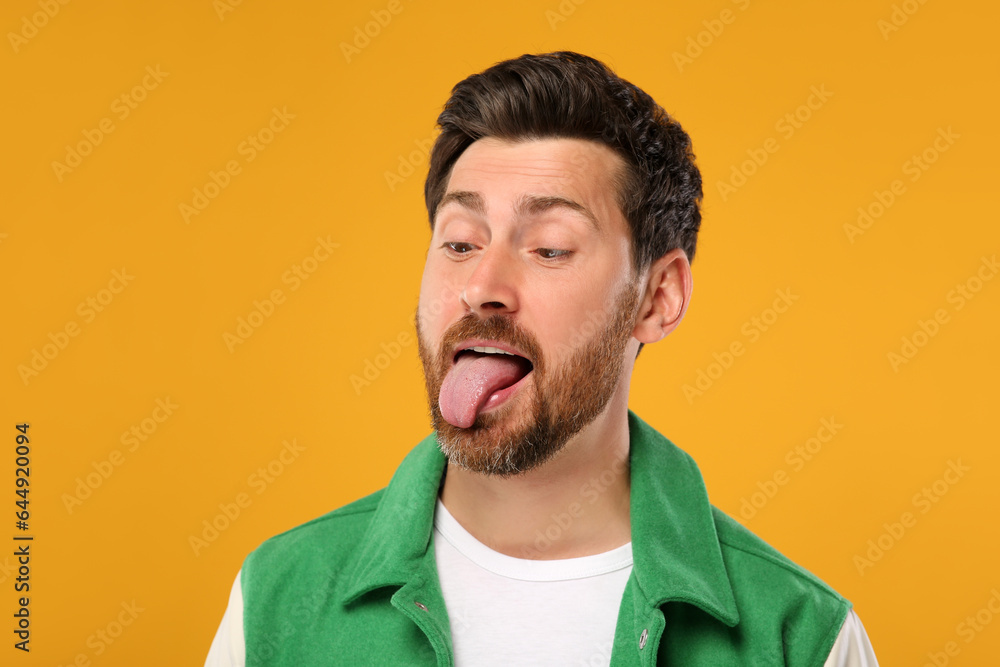 Man showing his tongue on orange background Man showing his tongue on orange background