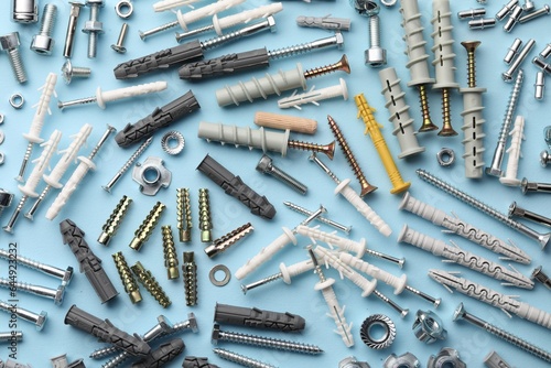 Photos Many different fasteners and dowels on light blue background, flat lay