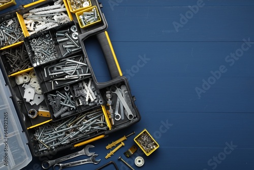 Organizer with many different fasteners and wrenches on blue wooden table, flat lay. Space for text