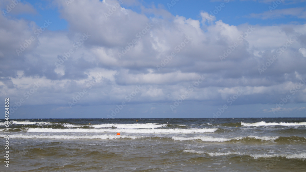 Baltic sea in Polish town Kolobrzeg. Cold sea. Clouds in the sea. Waves on the beach.
