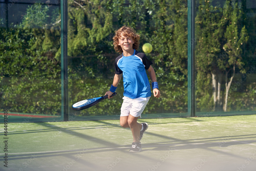 Obraz premium Happy boy playing padel on court at daytime