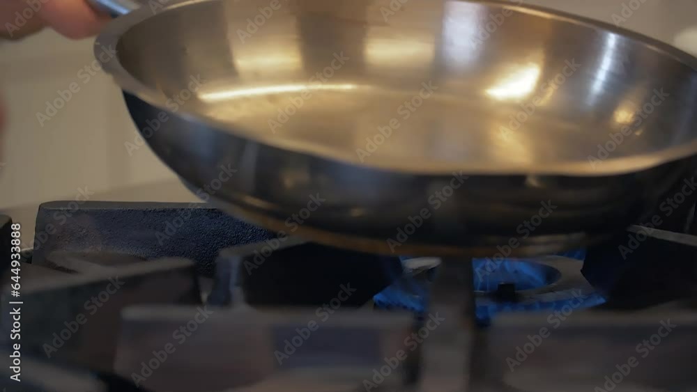 The chef is putting the pan on the burning fire for cooking. The chef is putting the pan on the burning fire for cooking.