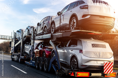 Tow truck car carrier semi trailer on highway carrying batch of new wrapped electric SUVs on motorway road at sunset evening time. Business distribution logistics service. Lorry driving highway © Kirill Gorlov