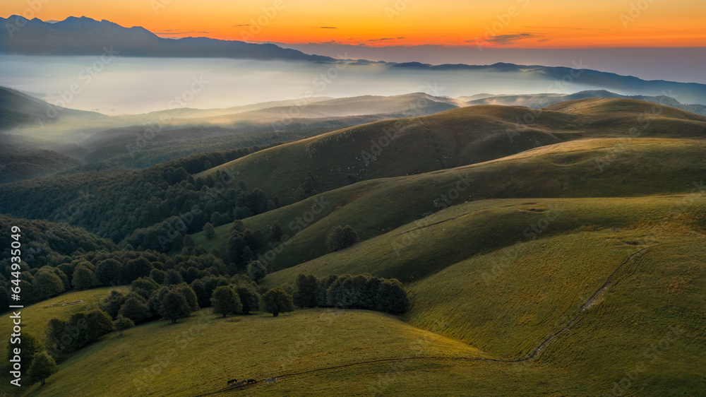 Fototapeta premium Mountain panorama with fog and green meadows. Clouds at sunrise