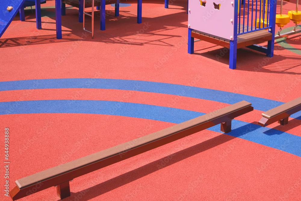 Kids balance beams with playground equipment on colorful orange and blue rubber floor in kindergarten school