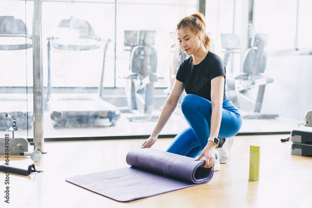 Fitness woman in sport club studio with yoga mat. Young woman roll pilates mat at a fitness training class.