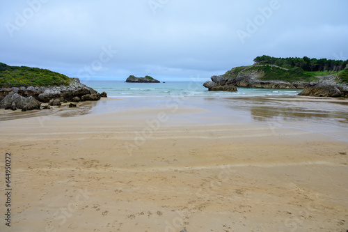 View on Playa de Palombina Las Camaras in Celorio, Green coast of Asturias, North Spain with sandy beaches, cliffs, hidden caves, green fields and mountains. © barmalini