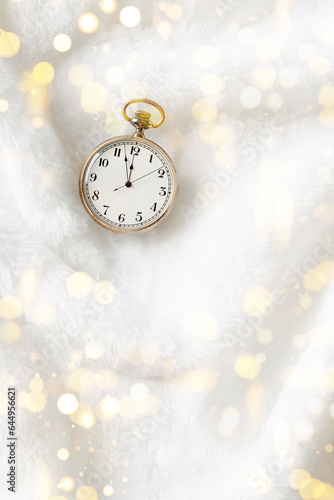 Vintage pocket watch showing New Year eve, holiday midnight on clock face, twelve hour, old watch on white fur background, copy space. New Year, Christmas, xmas concept, golden shiny bokeh