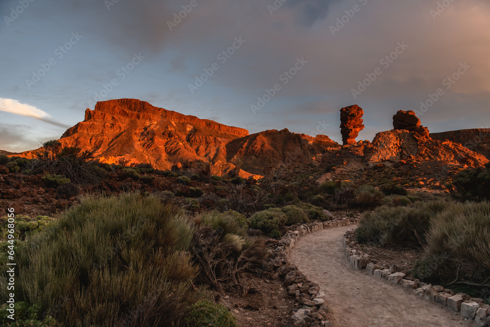 Mountain path on the sunset with a sunlitted rock in a distance