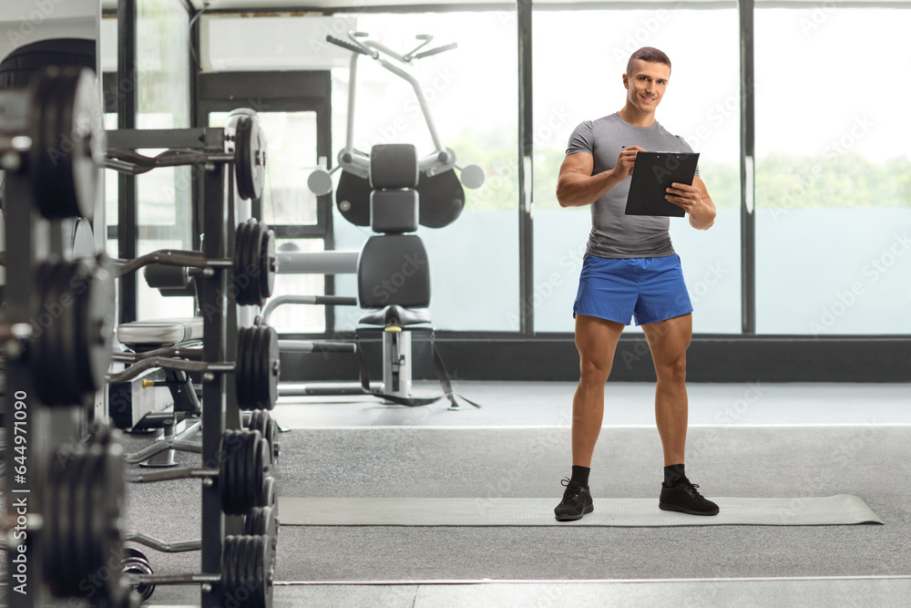 Full length portrait of a fitness instructor writing a document in a gym Full length portrait of a fitness instructor writing a document in a gym
