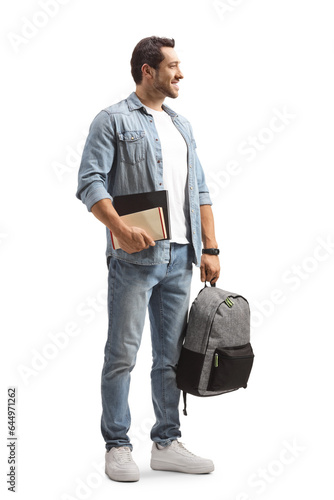 Full length shot of a casual man holding a backpack and books and looking to the side