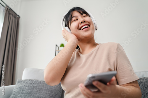 Young woman listening to music with headphone and relaxing while sitting on the sofa at home.