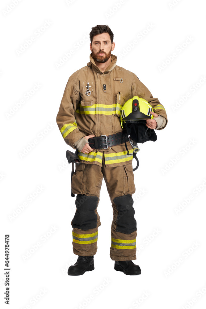 Tired bearded firefighter in uniform, holding protective helmet. Front view of dark-haired male rescuer with safety helmet keeping hand on waist belt, isolated on white studio background. Job concept.