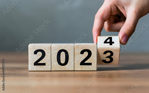 Hand flip wooden cube with the number 2023 to 2024. Happy new year 2024, Merry Christmas and Happy New Year, blue background. 2024 new year idea concept