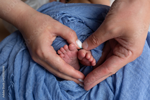 feet of a newborn baby in the hands of parents. legs on a blue background. baby feet