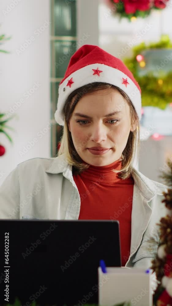 Vertical video Close up portrait of bookkeeper in Christmas decorated office checking documents for accuracy. Employee solving tasks at computer desk in xmas ornate workspace during winter holiday Vertical video Close up portrait of bookkeeper in Christmas decorated office checking documents for accuracy. Employee solving tasks at computer desk in xmas ornate workspace during winter holiday