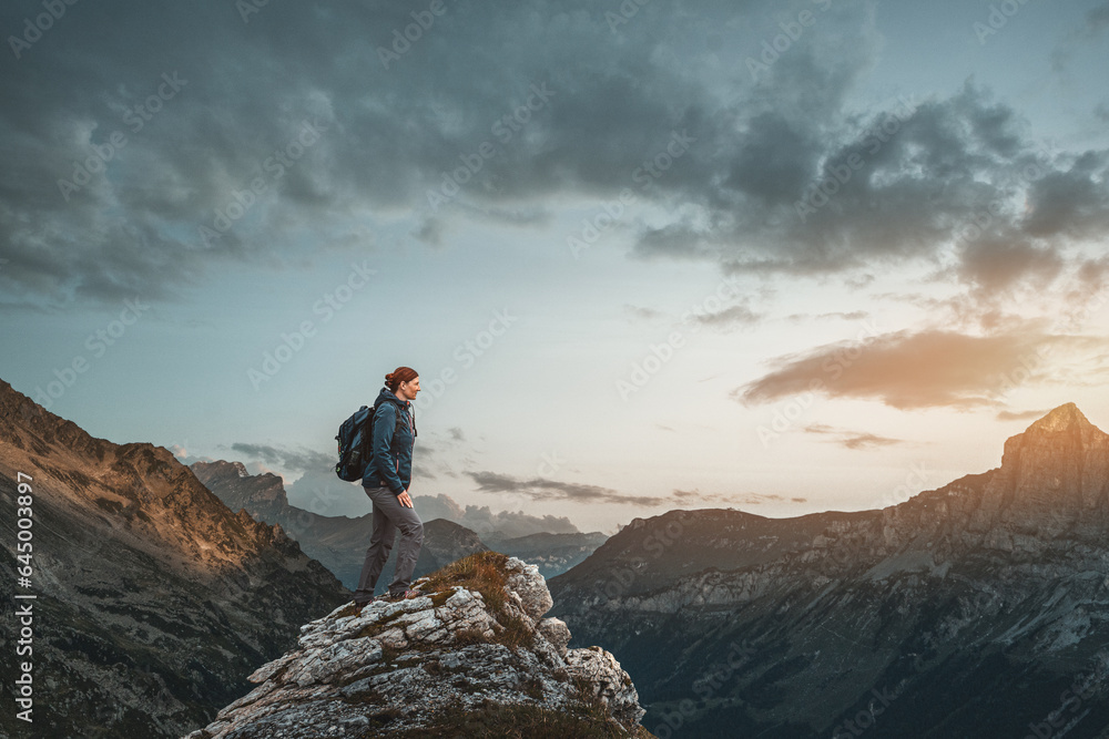Fototapeta premium Wanderin auf einem Berggifpel bei Sonnenaufgang