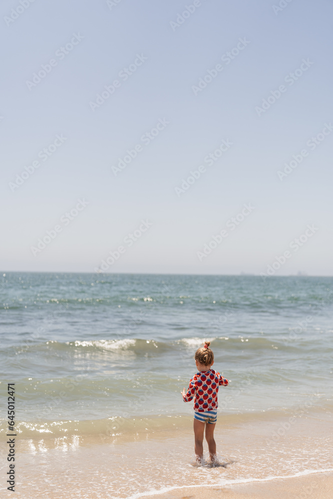 child standing in the ocean on the beach