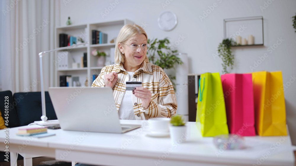 Woman paying for goods with a credit card, surprised with a fast delivery and shopping bags on her desk