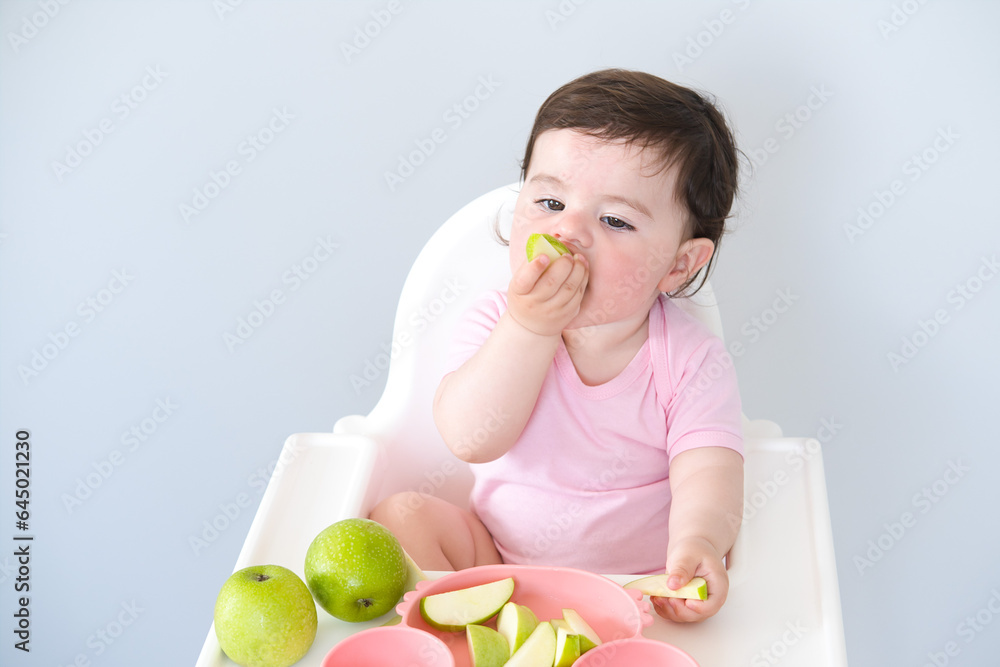 baby eating apple sitting in a high chair. weaning baby eating apple sitting in a high chair. weaning