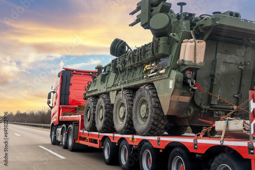 Back view armoured personnel carrier stryker with air defense system trailer hauler carrier truck drive military convoy highway road. US troops moving reloceation force reinforcement eastern Europe photo