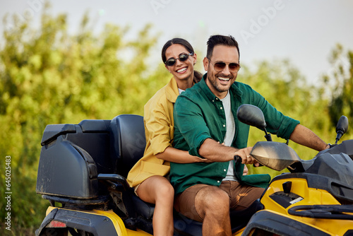 Portrait of a smiling love couple having a quad bike ride in nature. © bnenin