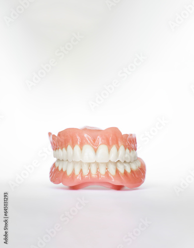 Vertical shot of dentures over white background with copy space. Dental plan. Dentistry prosthesis. Dental Health