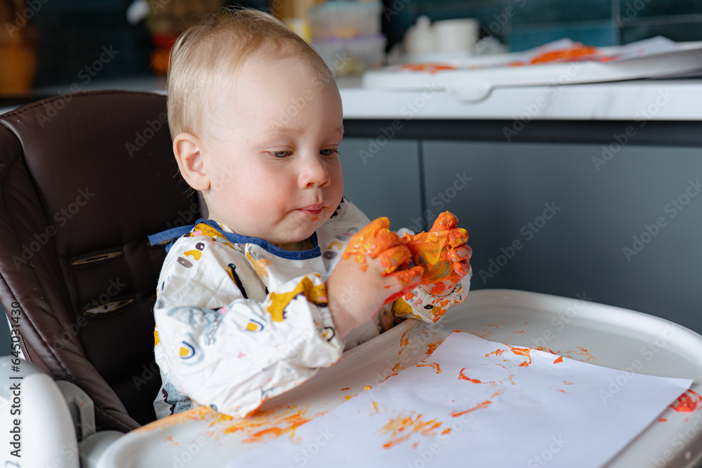 Finger painting. Cute little boy painting with fingers at home. Close-up of child's hand in colorful paints. Early education concept. Sensory play. Development of fine motor skills. Finger painting. Cute little boy painting with fingers at home. Close-up of child's hand in colorful paints. Early education concept. Sensory play. Development of fine motor skills.